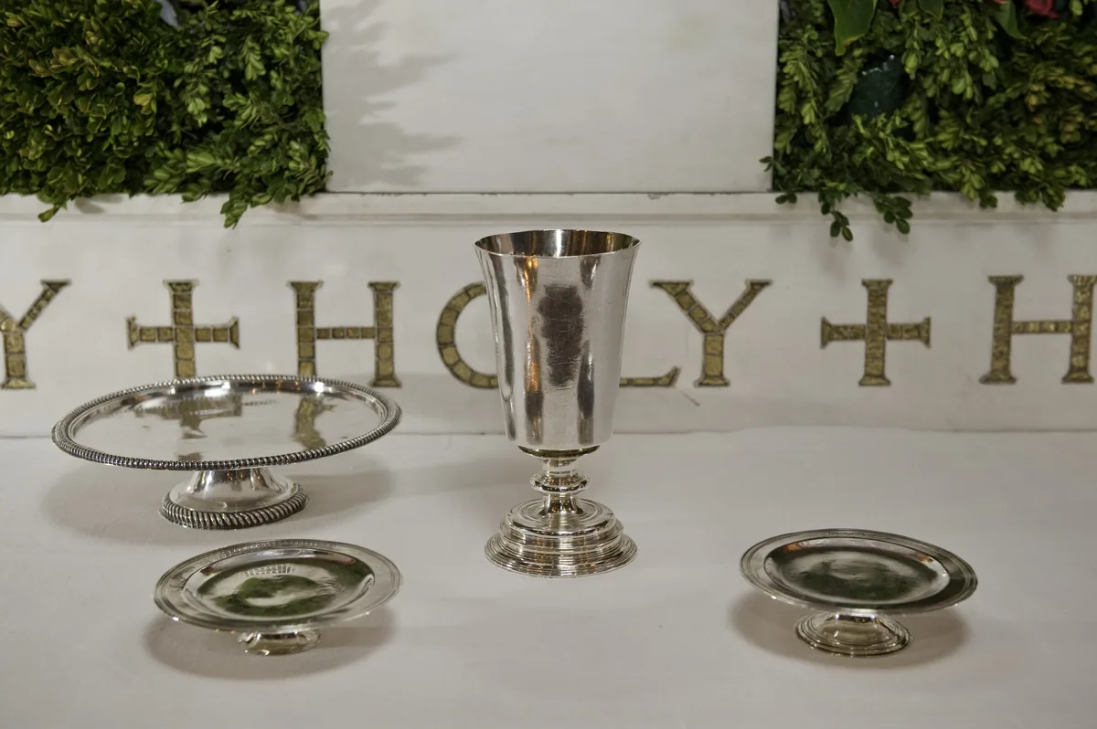 The communion silver on the altar at St. John's: a tall silver chalice between two small patens, with a larger footed plate beside them