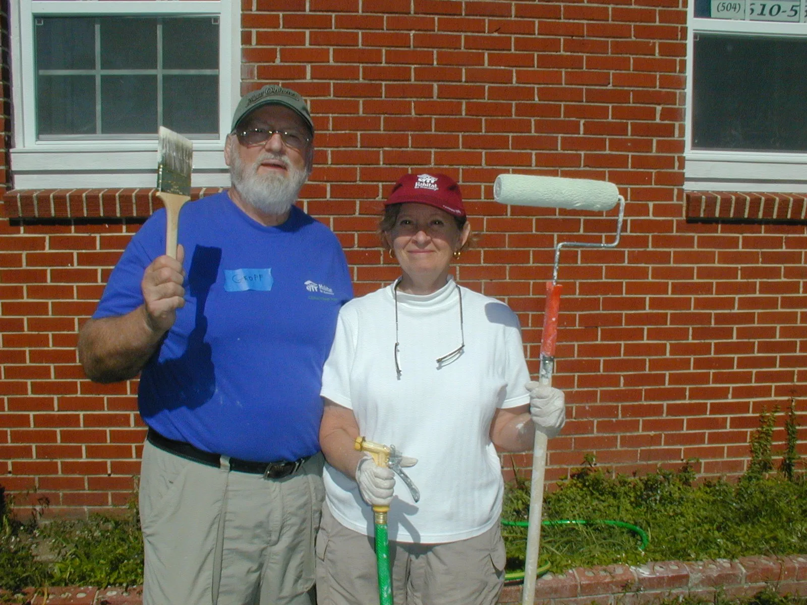 Two St. John's volunteers with a paintbrush and a roller outside a house in New Orleans