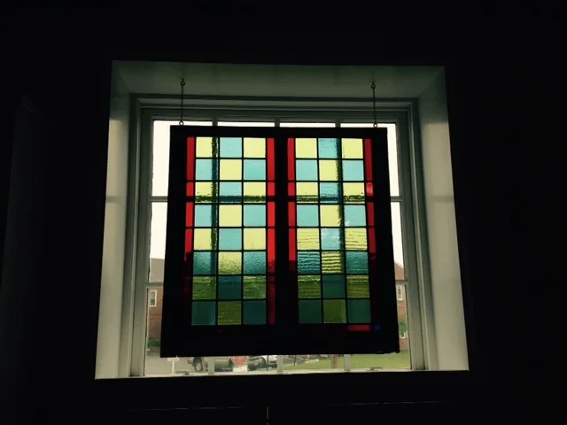 The restored stained glass panel hanging in a window