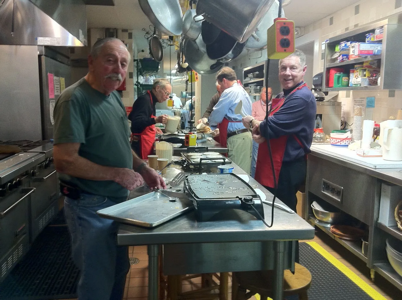 Men cooking pancakes in the parish hall kitchen